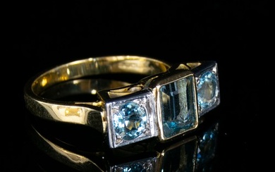 An 18ct yellow and white gold aquamarine trilogy ring, a cen...