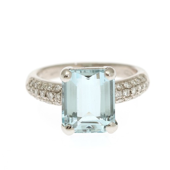 An aquamarine and diamond ring set with a fancy-cut aqumarine flanked by numerous brilliant-cut diamonds. Str. 55.