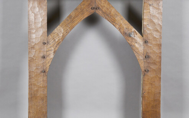 An early 20th century Arts and Crafts oak fire surround, the arched frame with pegged joints and ove