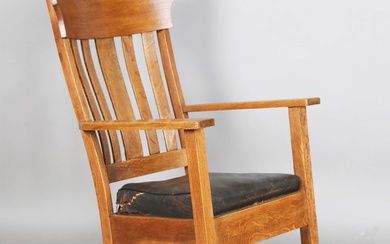 An early 20th century Arts and Crafts oak framed rocking armchair, in the manner of Gustav Stickley