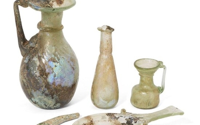 Four Roman glass vessels, circa 2nd-4th Century A.D. Including a small pale green glass skillet, 13.8cm long, 7.2cm diam of bowl; a green glass jug with, the body with diagonal moulded rib decoration, an applied band of trailing around the neck and...