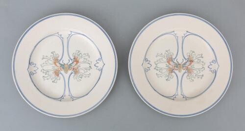 Two ceramic breakfast plates, both decorated with linear pattern and butterfly, matt white glazed, designed by Klaas Vet, circa 1915, marked underneath with painter's initials.