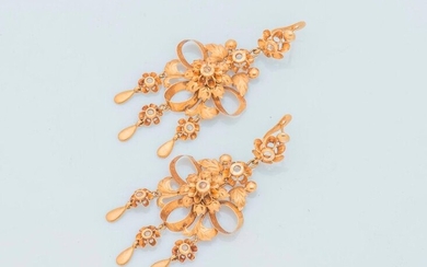 Pair of 18 karat yellow gold earrings (750 thousandths) drawing a ribbon tied into four loops in a foliage, centered by a flower set with a white stone, holding three pendants dressed with flowers and drops, surmounted by two flowers.