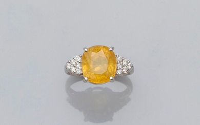 Ring in white gold, 750 MM, set with a cushion/oval treated yellow sapphire weighing 5.52 carats and set with twelve brilliants, size: 52, weight: 4.9gr. gross.