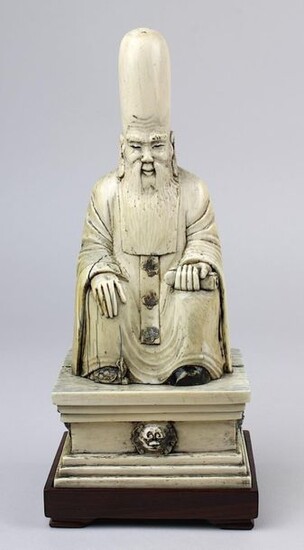 Sitting Shou Xing made of mammoth ivory, China around 1920, the god of longevity as a bearded man with an overly high forehead sitting on a stool on a pedestal, in his hand a scroll, under one foot a turtle peeping out, figure and pedestal carved from...