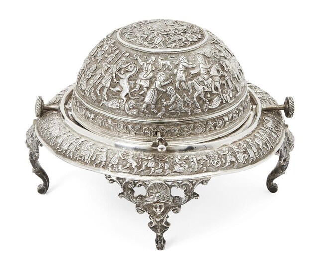 A Qajar engraved silver serving dish, Iran, late 19th-early 20th century, on three openwork feet with face, elaborately decorated to exterior with Achaemenid revival scenes the top of the dome with flowers and birds within a roundel, 25cm. diam...