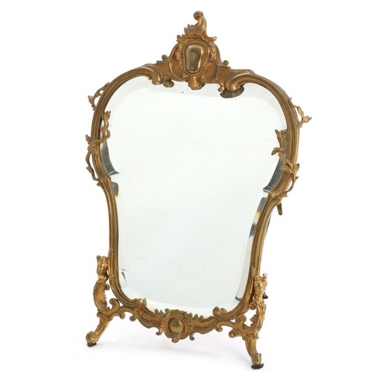 A Rococo style table mirror in a bronze frame, cast with female faces, foliage and c-scrolls. Circa 1900. H. 39 cm.