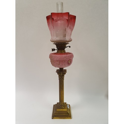 A brass oil lamp, with a ruby glass shade, pink glass well, ...
