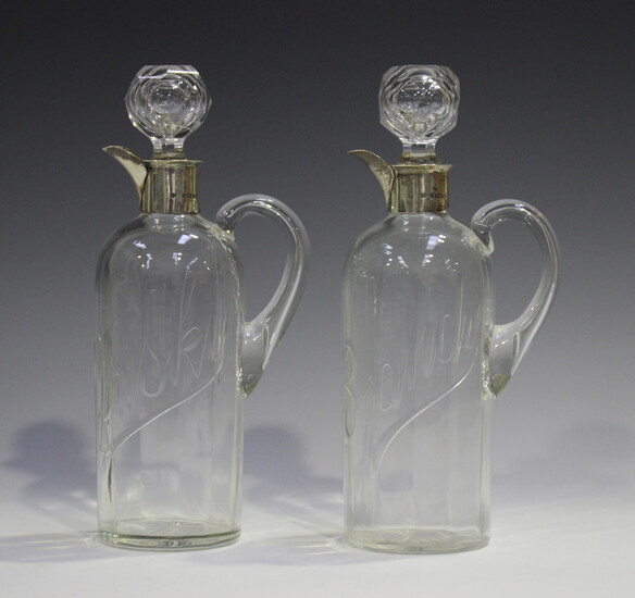 A pair of late Victorian silver mounted clear glass spirit flasks and stoppers, each cylindrical bod
