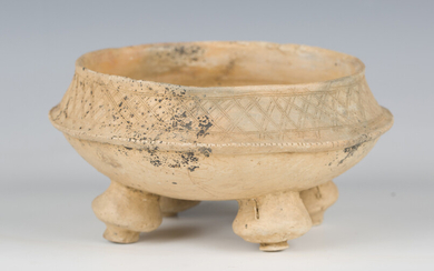 A pre-Columbian earthenware bowl, the waisted rim with incised decoration, raised on four bulbous ra