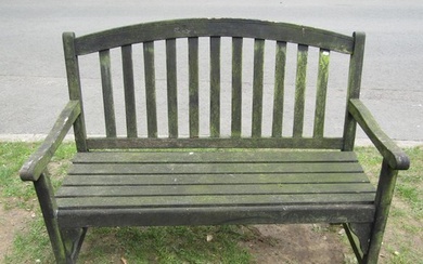 A weathered teak two seat garden bench with slatted seat and...