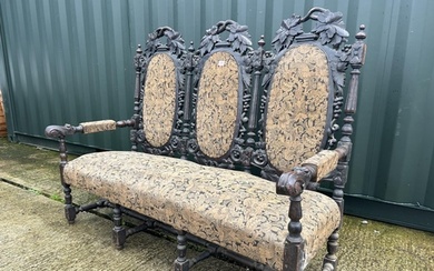 An antique Jacobean style carved oak three seater settle wit...