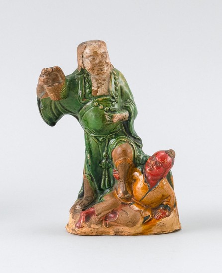 CHINESE POTTERY FIGURE GROUP In the form of a sennin in green robes subduing a red-faced demon. Marbled calligraphy on back. Height...