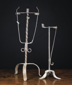 Two 18th Century Style Wrought Iron Peermen with Candle sockets: One having two sprung rush holders flanking a central candle socket on a wrythen stem and tripod base 24 in (61 cm) high. The other 18½ in (47 cm) high.