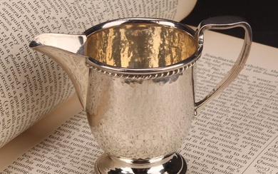 A E Jones - an Arts and Crafts silver pedestal cream jug, ro...
