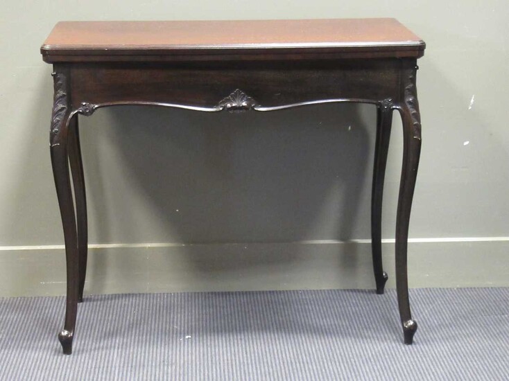 A late Victorian mahogany fold over swivel top card table with moulded frieze on carved cabriole
