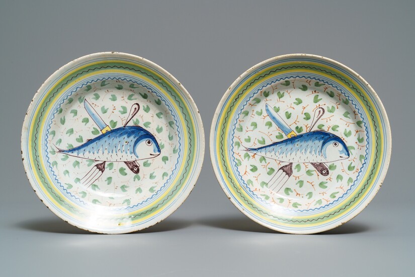 A pair of polychrome Brussels faience 'fish and cutlery' plates, 18th C.