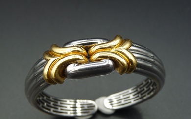 BULGARI : Bracelet rigide ouvert articulé en acier et or jaune 18K (750/oo) à motifs...