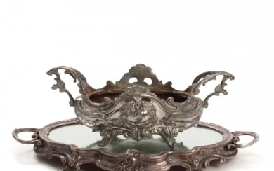 Jardinière de style Louis XV en metal argente et posee sur un plateau decoratif avec...