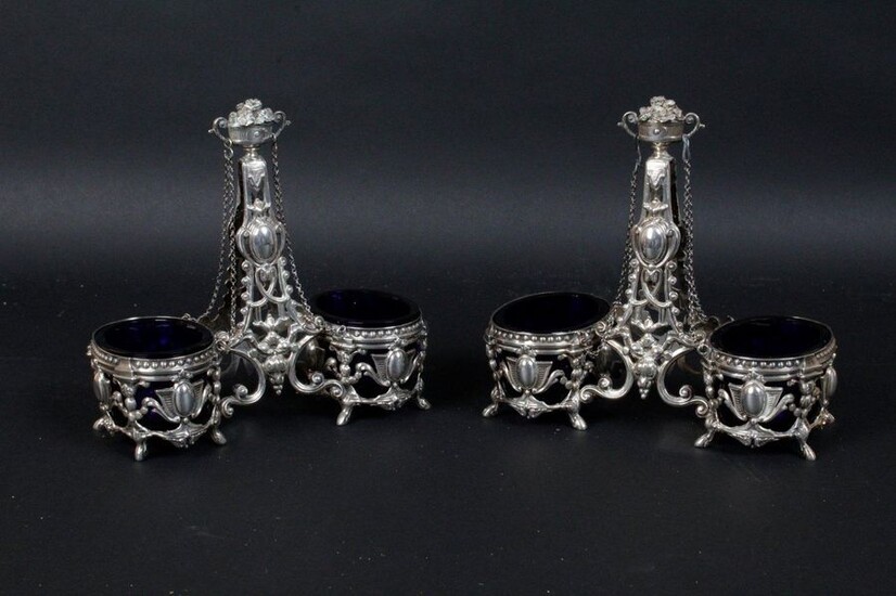 Pair of 950 sterling silver double salt pans on hoof feet decorated with leaf cartridges. The central socket ended by a floral urn. The interiors are in blue crystal. AM/R/ Minerva, late 19th Height: 15 cm Weight: 320 g AM/R/ Minerva, late 19th...