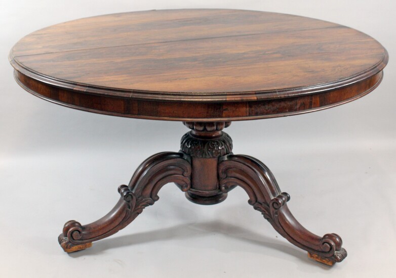 Tavolo rotondo in legno di palissandro, gamba centrale sorretta da quattro piedi a volute, altezza cm.73, diametro cm.132, (difetti)