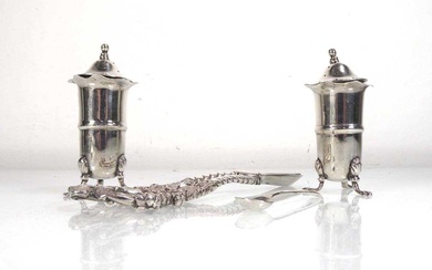 A pair of Edwardian silver peppers, each on three outswept...
