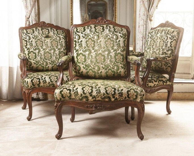 A suite of three armchairs à la reine in moulded and carved natural wood with flower decoration. Moving backrest, whiplash armrest supports, curved legs.
