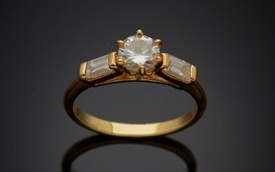 Solitaire en or jaune 18K 750‰, paré d’un diamant de taille brillant épaulé de deux...