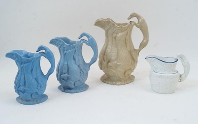 Three relief moulded jugs, each with a continuous frieze of game, the handles in the form of greyhounds, comprising: the largest in cream, 23.8cm high, another in light blue, 18cm high, and the smallest in light blue, 15.3cm high, each with applied...