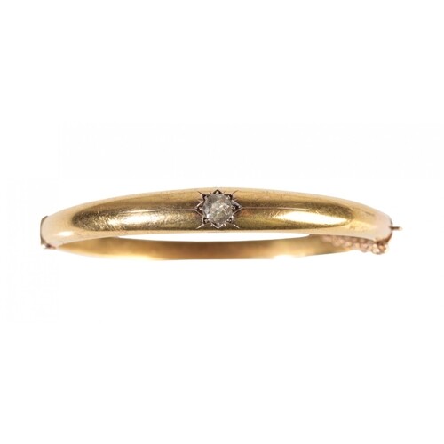 A GOLD AND DIAMOND BANGLE set with a solitaire round-cut dia...