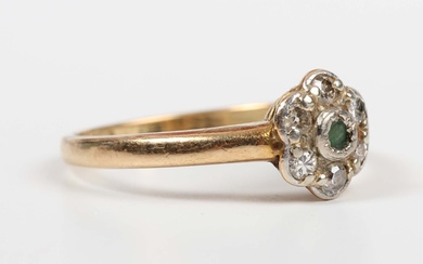 A gold and platinum, emerald and diamond cluster ring, mounted with the circular cut emerald within