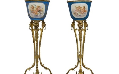 A pair of French gilt-bronze mounted Sevres jardinieres-on-stands, first half 20th century, the jardinieres painted with emblematic of music and the arts, the reverse flowers, the stands with lion-head mounts and ring handles, on foliate triform...