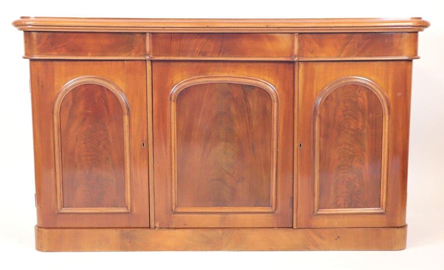 Mahogany sideboard, varnished in buff, opening by three doors and...
