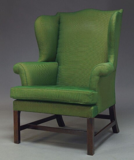 A George III wingback armchair with serpentine wings and loose...