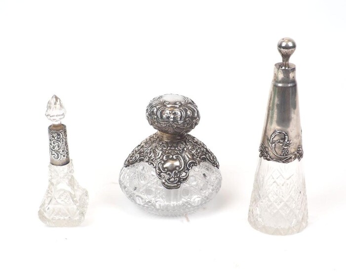 A German Art-Nouveau style silver mounted glass vanity bottle, of conical form with spherical silver stopper and cut glass bottle, 21.5cm high, together with an Edwardian example of bulbous form, Birmingham, c.1902, W J Myatt & Co., the pierced...