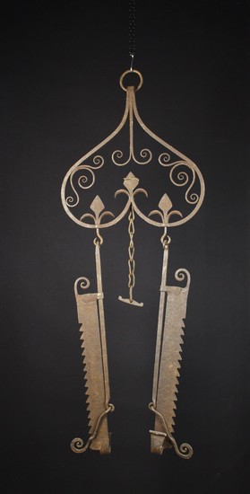 A Pair of 17th Century Style Trammel hooks hanging from a decorative wrought iron rack ornamented wi