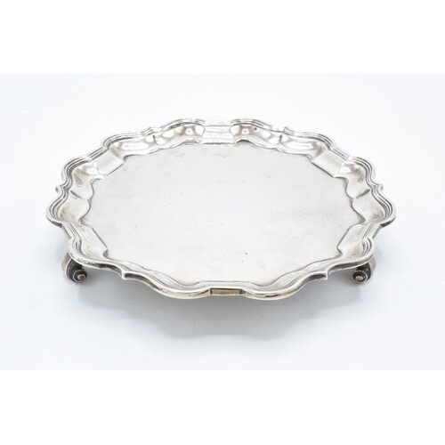 A hallmarked silver salver with shaped edge raised on three ...