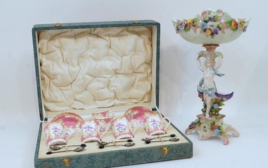 A set of six Minton Pink Cockatrice coffee cans and saucers, pattern no. 9646, with six silver coffee bean spoons, Birmingham, 1937, in fitted faux shagreen case, together with a Meissen style porcelain figural comport, the pierced basket with...