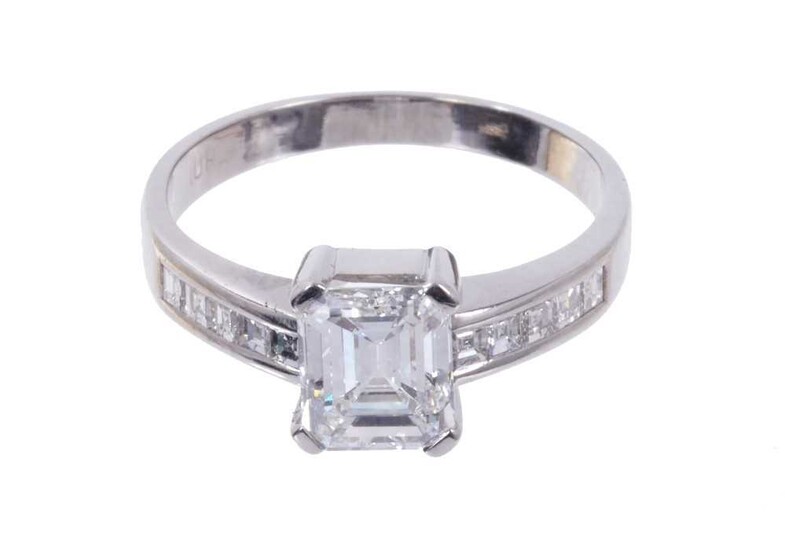 Diamond single stone ring with a step cut diamond weighing approximately 1.23 carats in four claw setting with further step cut diamonds to the shoulders. Ring size L.