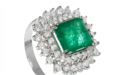 Ring in 18kt white gold. Model with central emerald of ca. 4.50 cts. and border of diamonds with