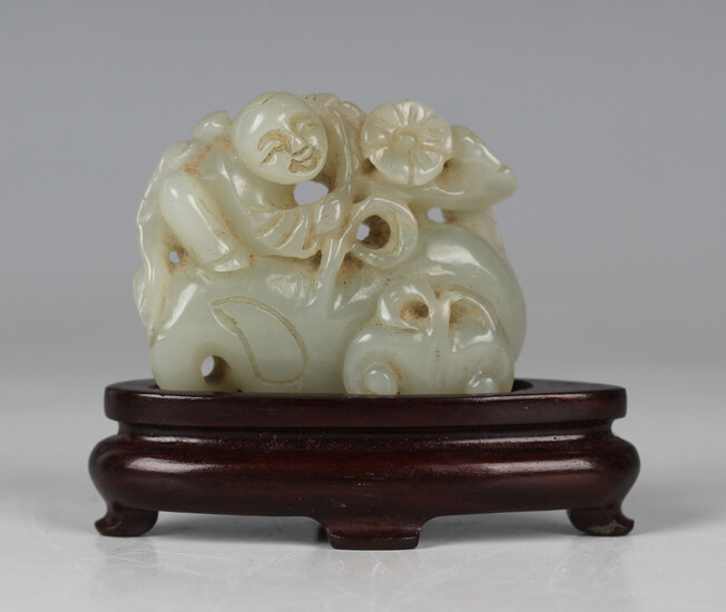 A Chinese pale celadon jade carving, 20th century, carved and pierced with a boy clasping a lotus br