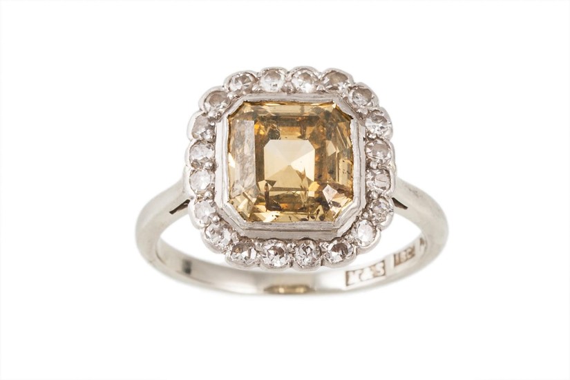 A DIAMOND CLUSTER RING, the emerald cut yellow diamond to a ...
