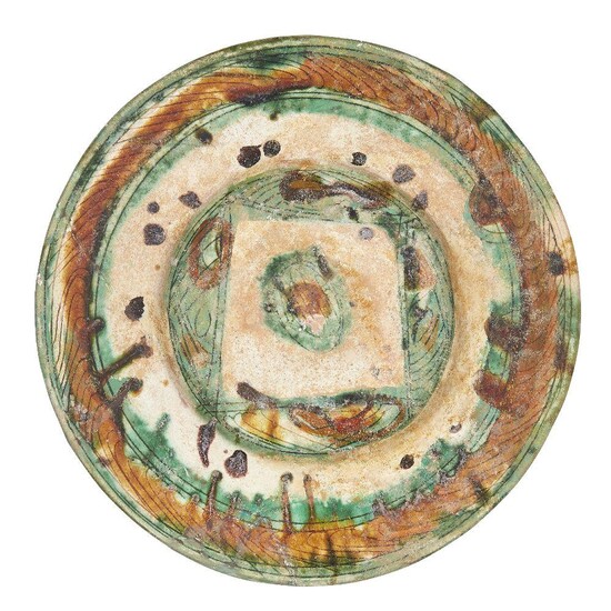 A Nishapur sgraffito splashware pottery dish, Iran, 10th century, the earthenware body incised to the well and rim, decorated with splashes of brown, green and yellow glazes, 26cm diameter Provenance: Private collection London since 1968