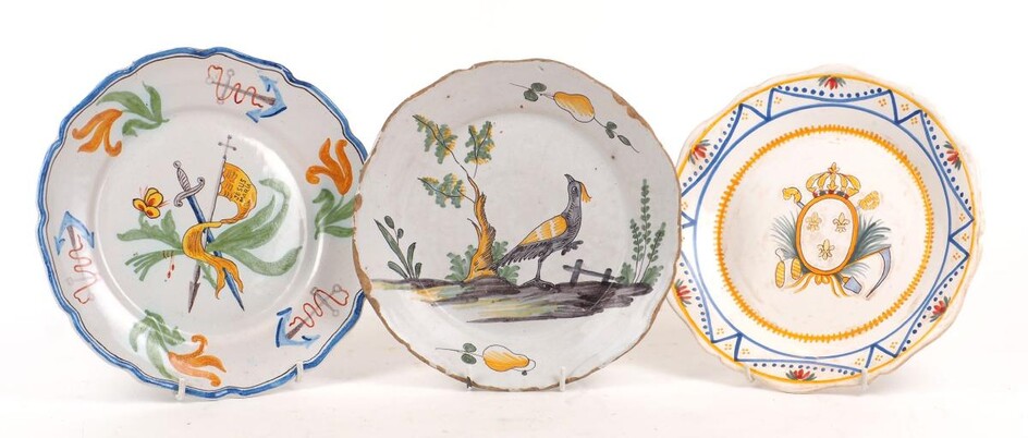 A group of three faience plates, 18th/19th century, comprising a Delft style deep plate with a stylised yellow-headed blackbird and tree to the centre and pears to the rim, indistinctly marked, 23cm diameter, a Spanish plate with sword and banner...