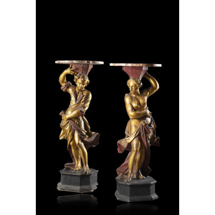 A pair of 18th-century Venetian carved, lacquered and gilded wooden gueridons with figural supports on ebonized wooden bases. Marble tops...