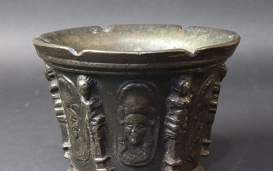 Bronze mortar with six ribs in the form of caryatids interspersed with six medallions of a face topped with a feather. Lyon or Puy en Velay. 17th century. Height 9,8 cm. Diameter 14.3 cm. Six notches cut in the upper edge