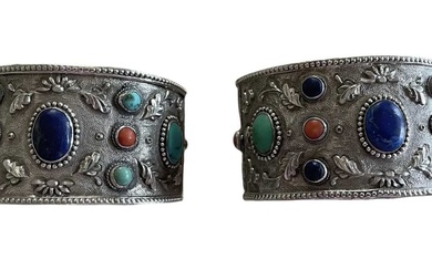 Pair of Chinese silver and gem set cuff bangles, each with a lapis lazuli, turquoise and coral cabochons on floral repoussé silver ground.