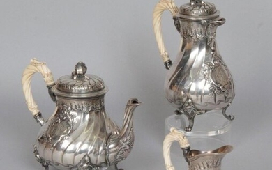 Three-piece silver 950 mils baluster-shaped service, with torsos ribbed and decorated with a monogrammed rocaille cartouche, the neck and lid underlined with combed friezes, the feet with foliated scrolls and fasteners, the handles carved in ivory. It...