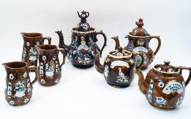A collection of Victorian Bargeware teapots and jugs, comprising: a large teapot and cover, with teapot finial and relief decorated with flowers and birds on a brown ground, marked DIAMOND JUBILEE LONG LIE OUR NOBLE QUEEN, 33cm high; three other...
