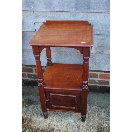 A mahogany bedside table, fitted cupboard, on turned support...